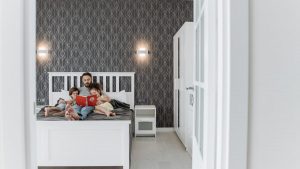 Father and children enjoy a bonding storytime in a cozy, modern bedroom setting.